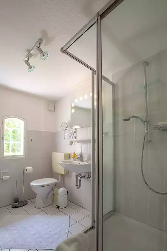 Badezimmer der Ferienwohnung Nordermühle auf Pellworm mit Dusche, WC, Waschbecken und kleinem Stallfenster