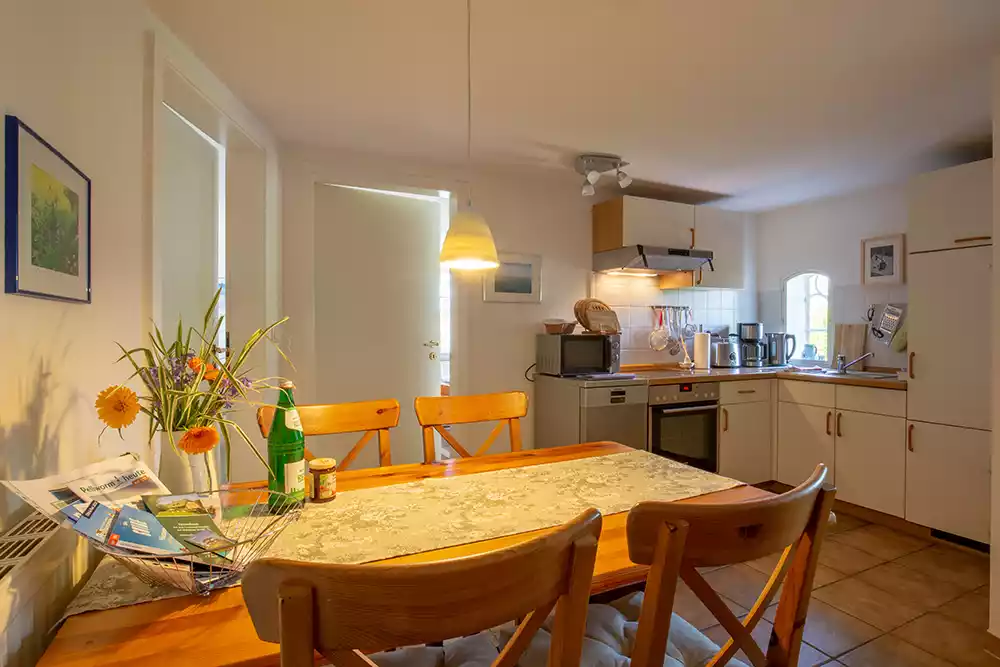 Küche der Ferienwohnung Nordermühle auf Pellworm mit Esstisch, Stühlen und voll ausgestatteter Küchenzeile