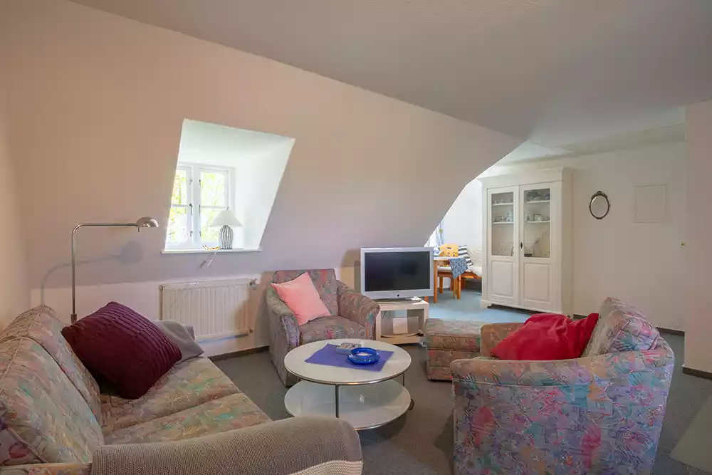 Wohnzimmer der Ferienwohnung Vogelkoje auf Pellworm mit Couchecke, Sesseln, Fernseher und Essbereich im Hintergrund