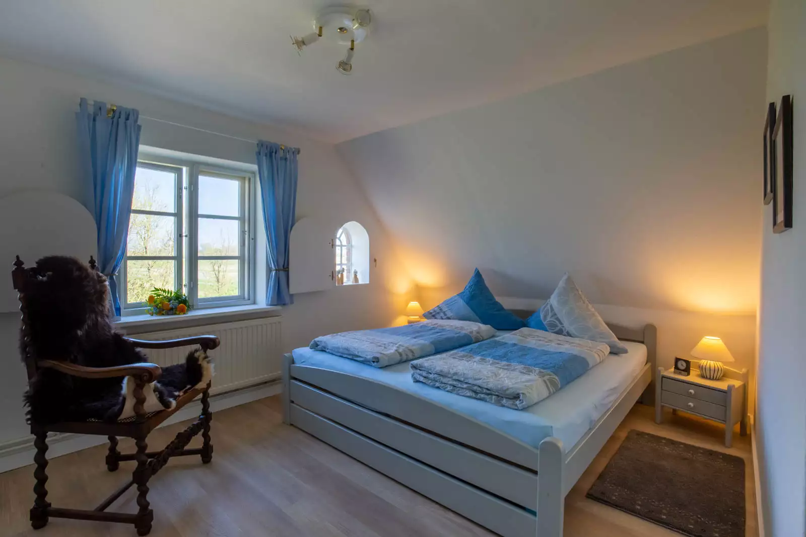 Schlafzimmer der Ferienwohnung Vogelkoje auf Pellworm mit Doppelbett, Fenster und Stuhl