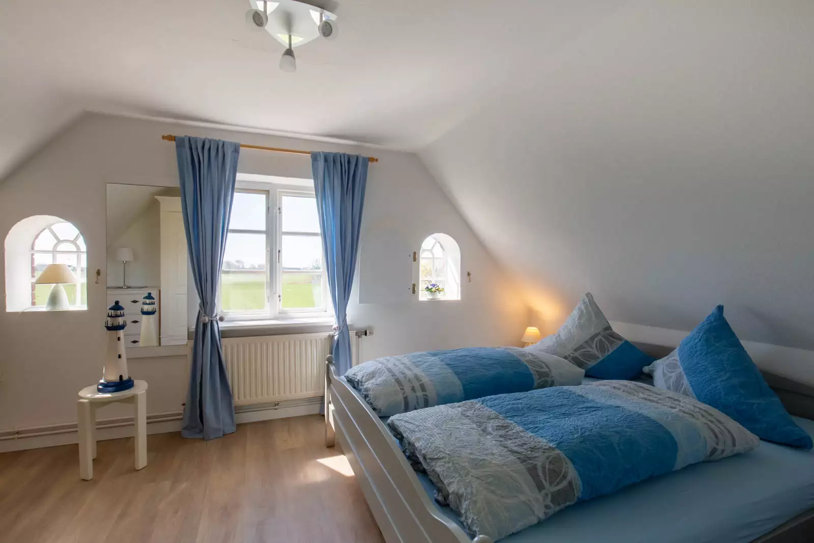 Schlafzimmer der Ferienwohnung Leuchtturm auf Pellworm mit Doppelbett und Fenster