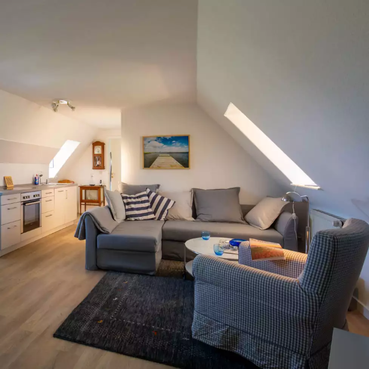 Wohnbereich der Ferienwohnung Vogelkoje auf Pellworm mit Couchecke und angeschnittener Küchenzeile