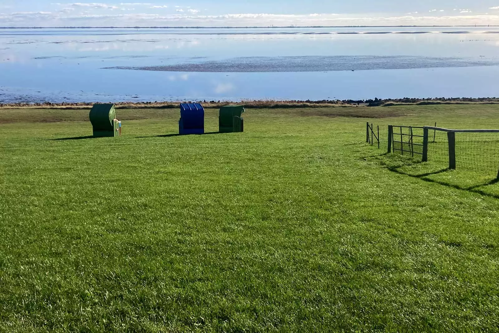 Blick vom Deich auf Pellworm zur Nordsee mit Strandkörben und weiter Küstenlandschaft