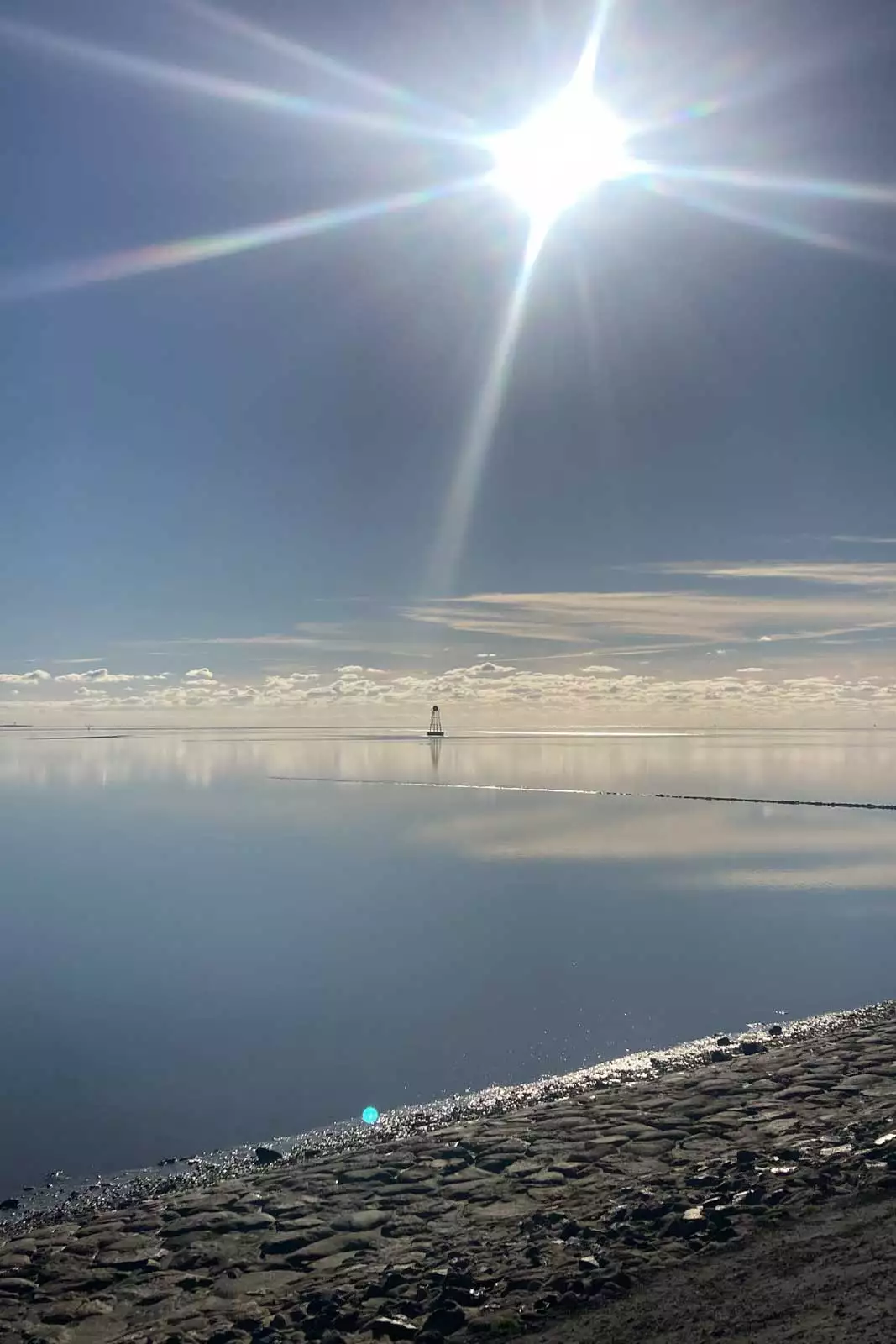 Spiegelglatte Nordsee vor Pellworm mit Blick auf das Unterfeuer an der Leuchtturmseite und weitem Horizont