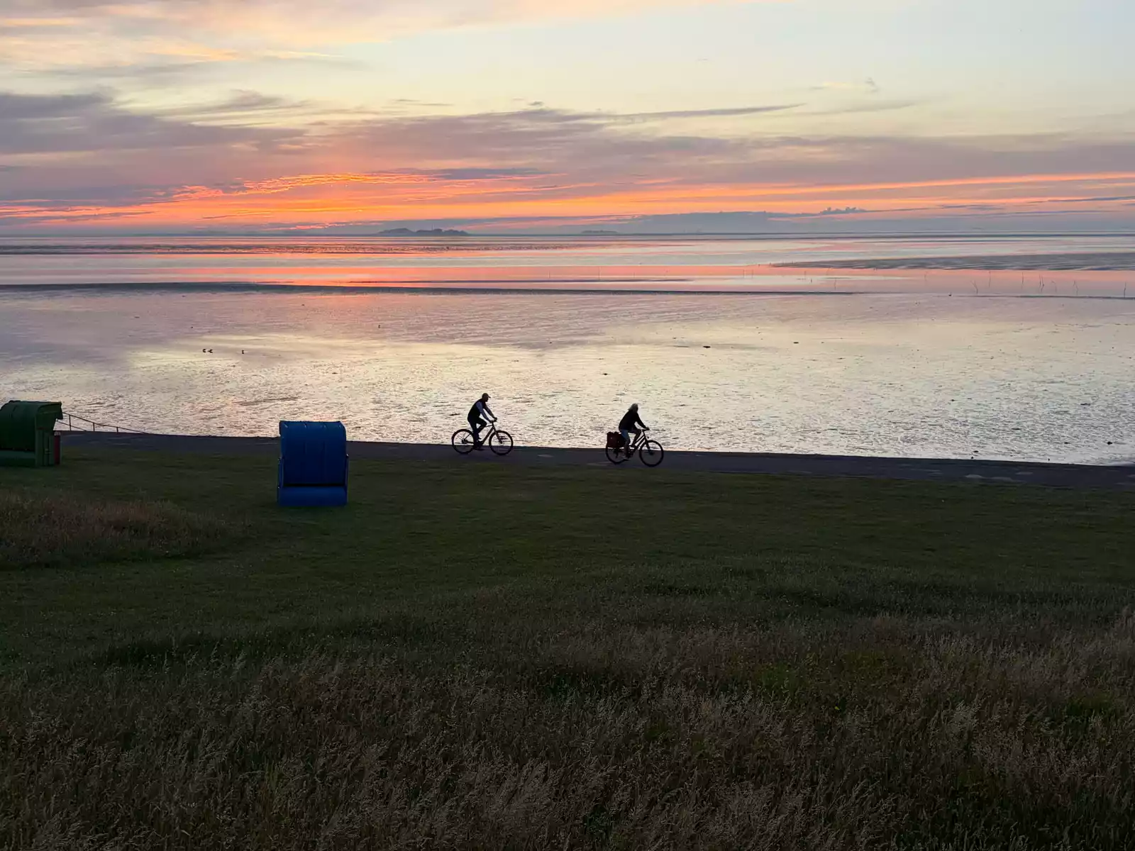 Fahrradfahrer umfahren die Insel Pellworm unten an der Nordsee auf dem befestigten Weg