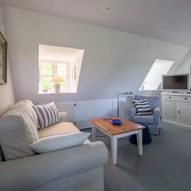 Wohnbereich der Ferienwohnung Leuchtturm auf Pellworm mit Couchecke, Fernseher und gemütlicher Atmosphäre