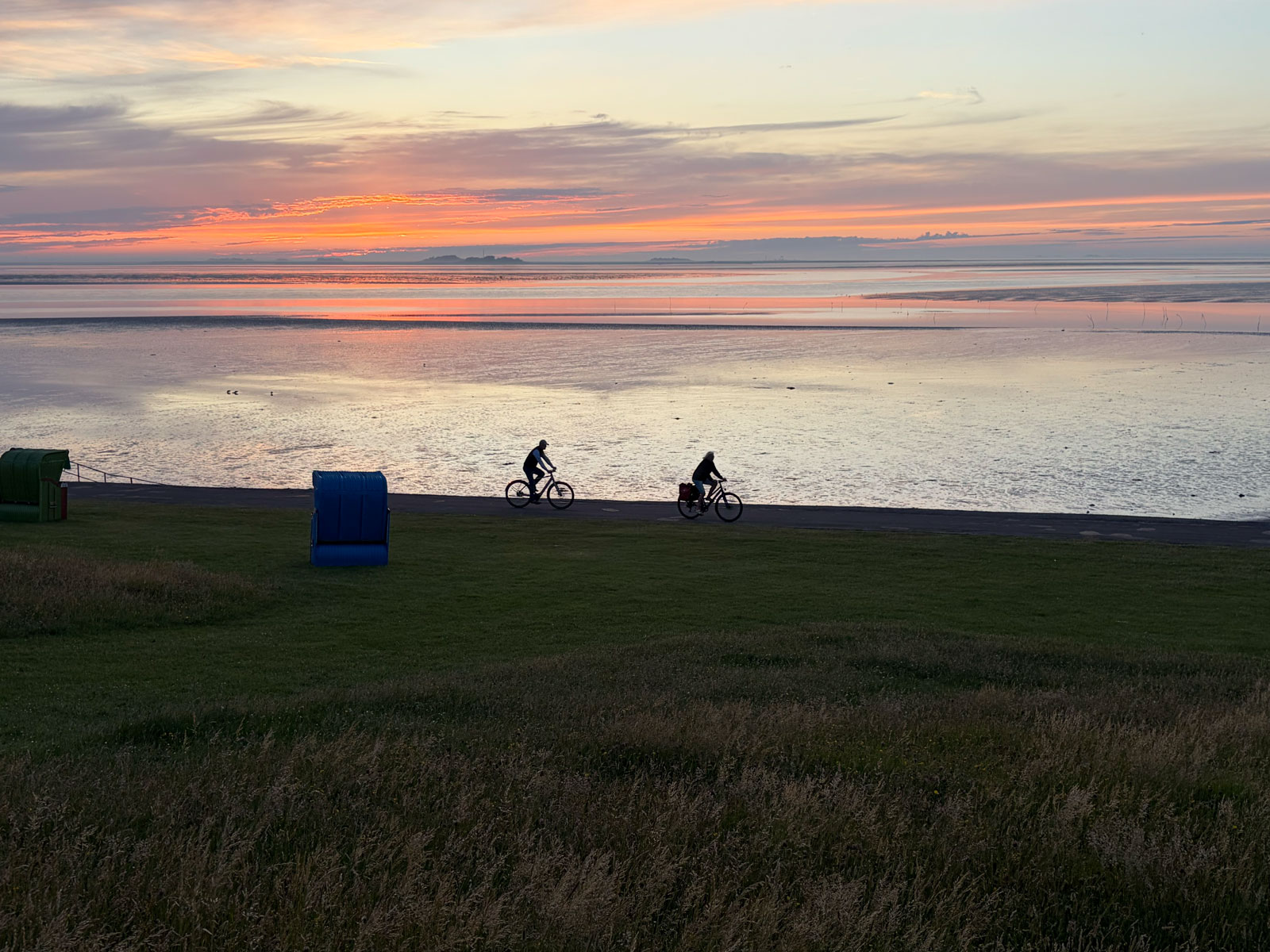 Zwei Fahrradfahrer am Deich entlang der Nordsee auf Pellworm Zwei Fahrradfahrer am Deich entlang der Nordsee auf Pellworm